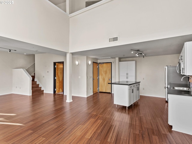 kitchen featuring sink, dark hardwood / wood-style flooring, white cabinets, track lighting, and a high ceiling