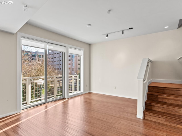 unfurnished living room with light wood-type flooring, rail lighting, and a wealth of natural light