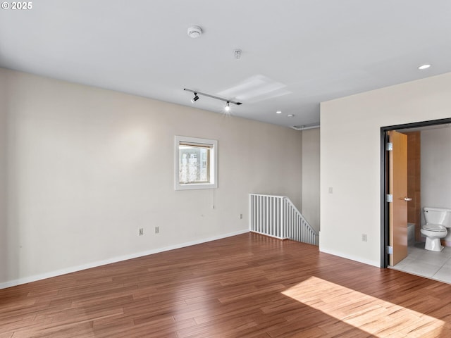 spare room with light hardwood / wood-style floors and track lighting