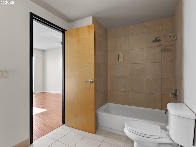 bathroom with toilet, tile patterned flooring, and tiled shower / bath