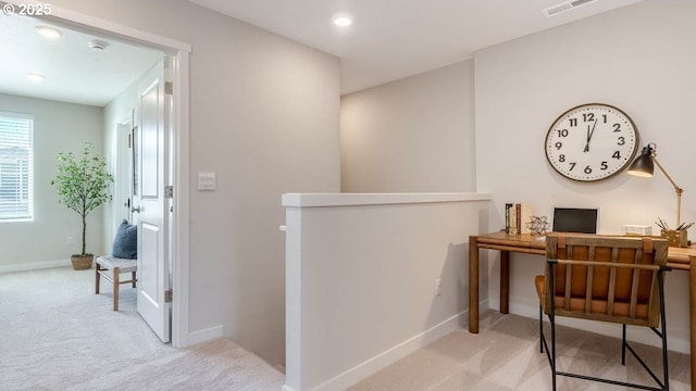office area with visible vents, baseboards, and light carpet