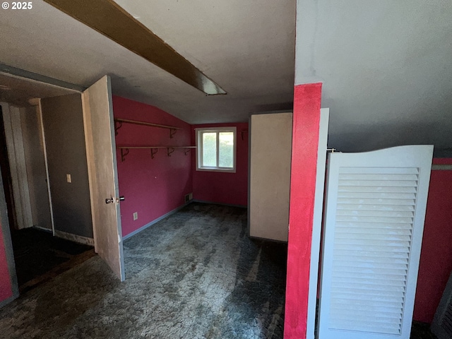 additional living space with vaulted ceiling and dark colored carpet