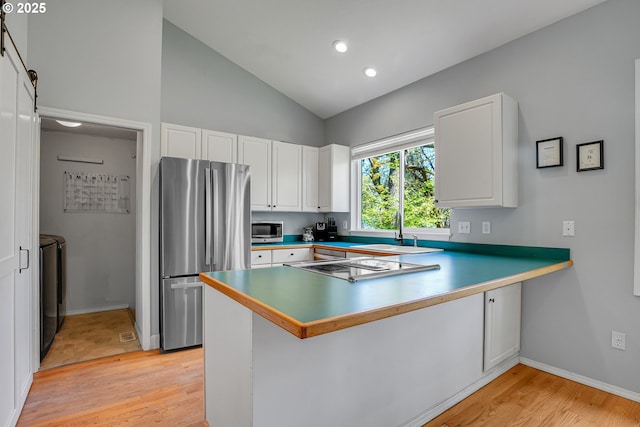 1223 NE 160th Ave, Portland, OR 97230 - kitchen featuring appliances with stainless steel finishes, light wood-type flooring, a sink, a peninsula, and washer and dryer