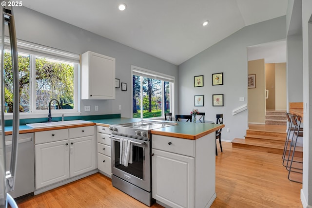 1223 NE 160th Ave, Portland, OR 97230 - kitchen featuring a peninsula, white cabinets, a sink, high end range, and vaulted ceiling