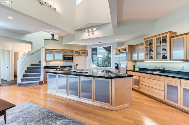 4300 SW Hewett Blvd, Portland, OR 97221 - kitchen with stainless steel appliances, light wood finished floors, an island with sink, dark countertops, and glass insert cabinets