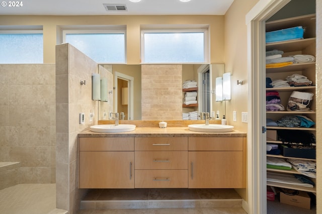 bathroom featuring vanity, a healthy amount of sunlight, and tiled shower