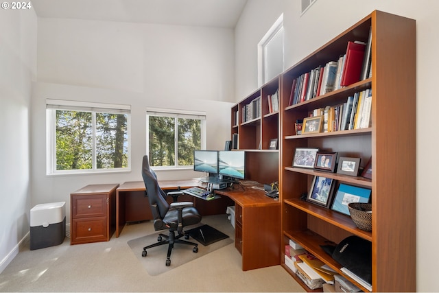 office area featuring a high ceiling and light colored carpet