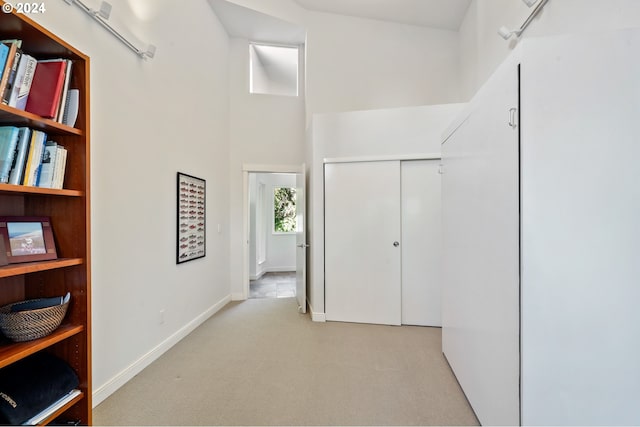 hall with a high ceiling and light colored carpet