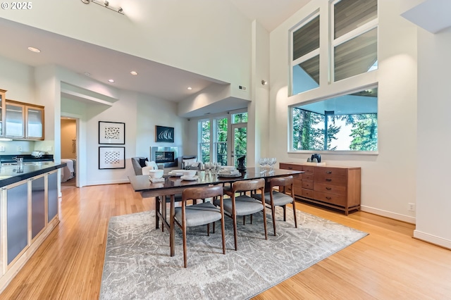 4300 SW Hewett Blvd, Portland, OR 97221 - dining room featuring light wood finished floors, a glass covered fireplace, a high ceiling, and recessed lighting