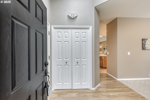 foyer with baseboards and light wood-style floors