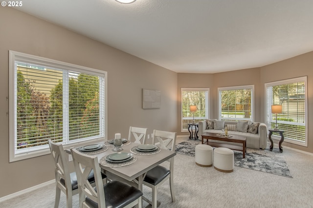 dining room featuring light colored carpet and baseboards