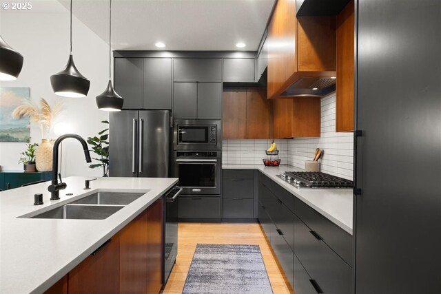 720 S 19th Pl, Ridgefield, WA 98642 - kitchen featuring stainless steel appliances, a sink, modern cabinets, pendant lighting, and light wood finished floors
