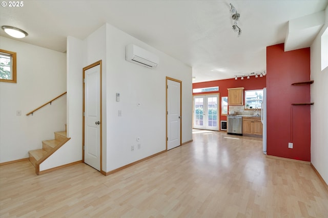 1106 Wilson St, Hood River, OR 97031 - unfurnished living room with rail lighting, a wall unit AC, light wood-style flooring, and stairs