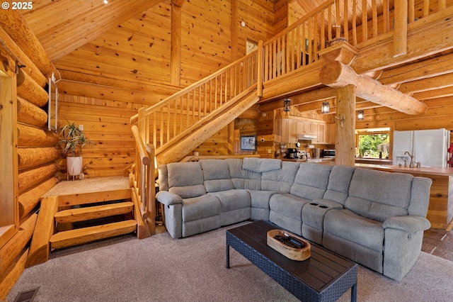 93011 Labeck Rd, Astoria, OR 97103 - living area featuring carpet flooring, stairs, high vaulted ceiling, and rustic walls