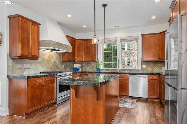 kitchen featuring a kitchen island, stainless steel appliances, dark wood-type flooring, and wall chimney range hood