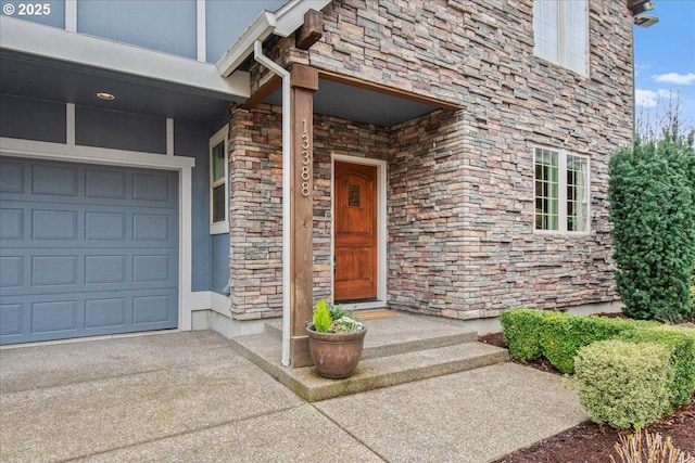 property entrance featuring concrete driveway, a garage, and stone siding