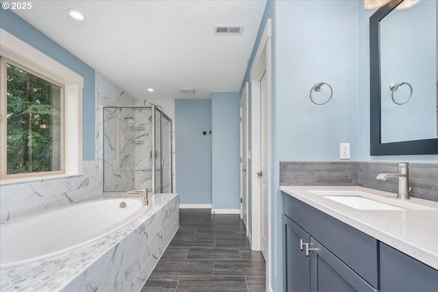 full bath featuring visible vents, a garden tub, a marble finish shower, baseboards, and vanity