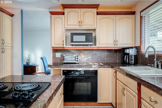 kitchen featuring light brown cabinetry, sink, backsplash, and black appliances