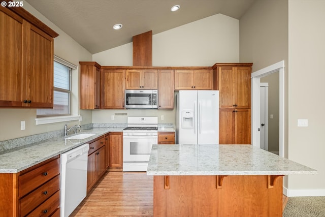 kitchen featuring a center island, a sink, brown cabinets, and white appliances