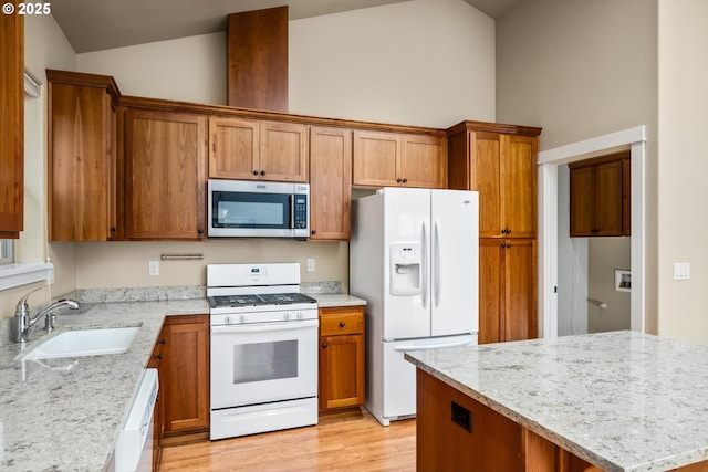 kitchen with white appliances, brown cabinetry, and a sink