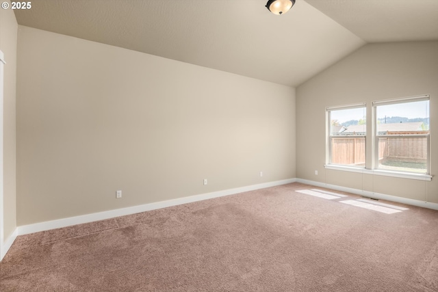 carpeted spare room with baseboards and vaulted ceiling