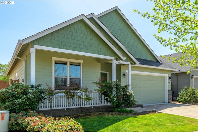 craftsman-style house with roof with shingles, an attached garage, driveway, and a front yard