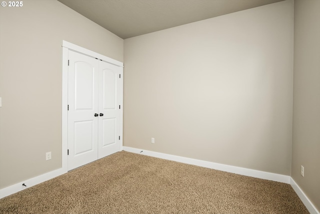 unfurnished bedroom featuring carpet floors, baseboards, and a closet