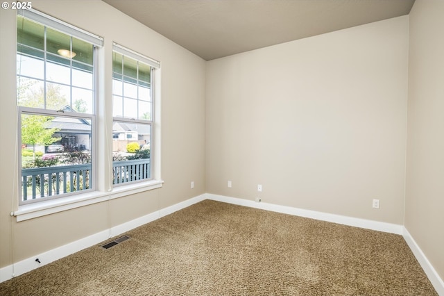 carpeted empty room featuring baseboards and visible vents