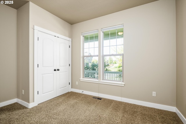 unfurnished bedroom featuring carpet floors, baseboards, visible vents, and a closet