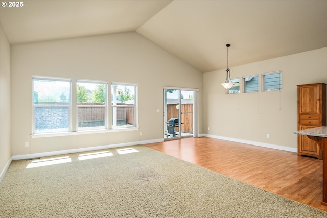 interior space with light colored carpet, high vaulted ceiling, light wood-style flooring, baseboards, and visible vents