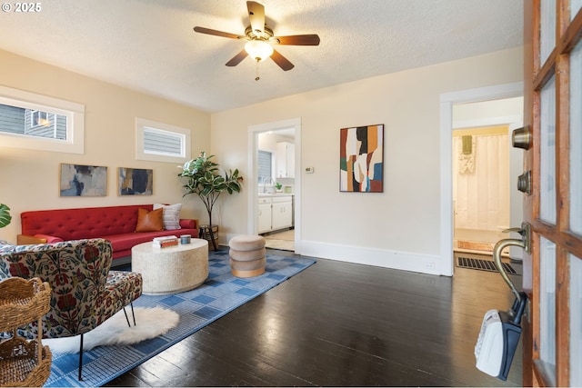 living room with ceiling fan, dark wood-type flooring, sink, and a textured ceiling