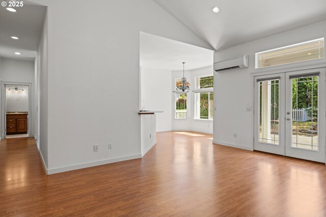 1249 Zebrawood St, Florence, OR 97439 - unfurnished room with a wall mounted air conditioner, high vaulted ceiling, recessed lighting, wood finished floors, and a chandelier