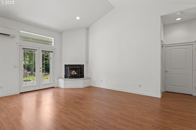 1249 Zebrawood St, Florence, OR 97439 - unfurnished living room with a wall mounted AC, wood finished floors, a warm lit fireplace, french doors, and vaulted ceiling