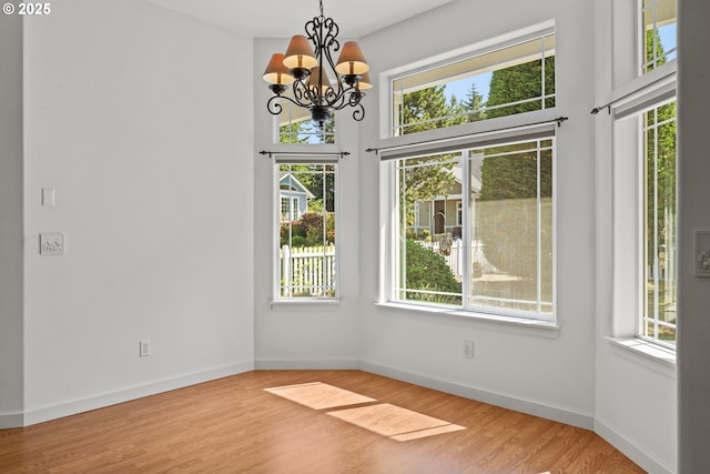 1249 Zebrawood St, Florence, OR 97439 - unfurnished dining area with healthy amount of natural light, a chandelier, wood finished floors, and baseboards