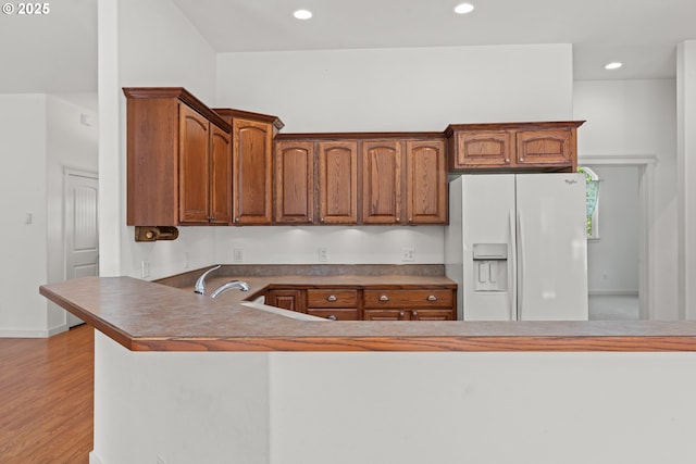 1249 Zebrawood St, Florence, OR 97439 - kitchen with white refrigerator with ice dispenser, brown cabinets, recessed lighting, light wood-style flooring, and a peninsula