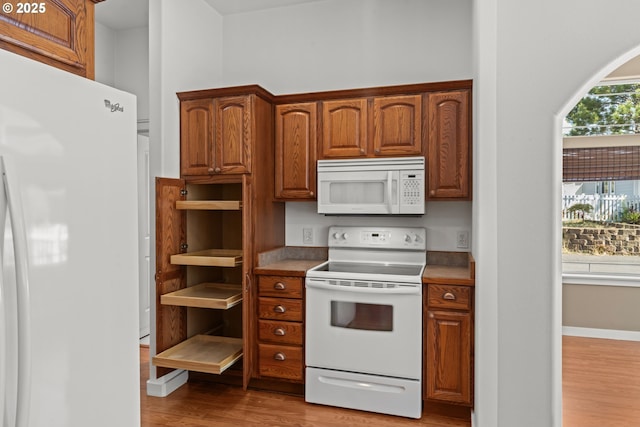 1249 Zebrawood St, Florence, OR 97439 - kitchen with white appliances, light wood finished floors, and brown cabinetry