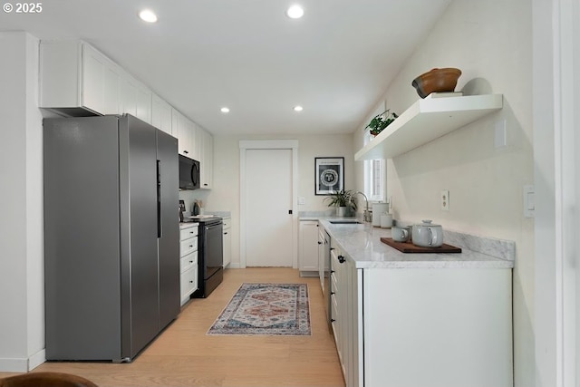4038 NE Multnomah St, Portland, OR 97232 - kitchen featuring black appliances, light wood-style flooring, white cabinets, light countertops, and recessed lighting
