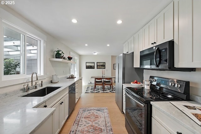 4038 NE Multnomah St, Portland, OR 97232 - kitchen with black appliances, white cabinetry, light wood-style flooring, recessed lighting, and light stone counters
