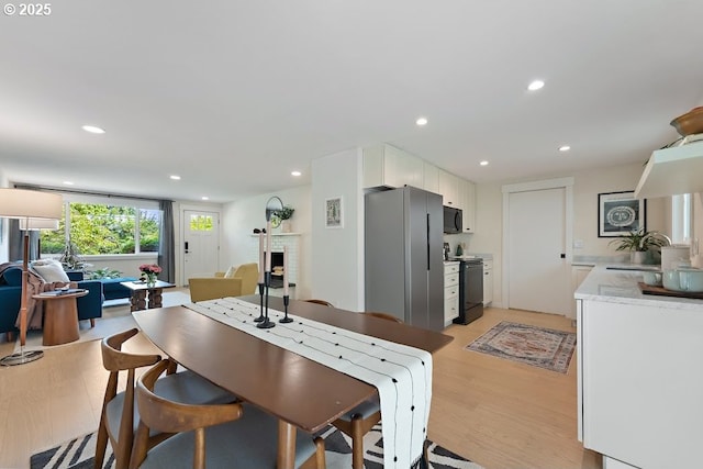 4038 NE Multnomah St, Portland, OR 97232 - kitchen featuring black appliances, light wood-style floors, white cabinets, recessed lighting, and open floor plan