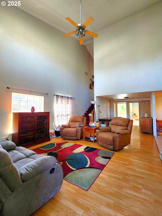 living area with a ceiling fan, wood finished floors, and high vaulted ceiling