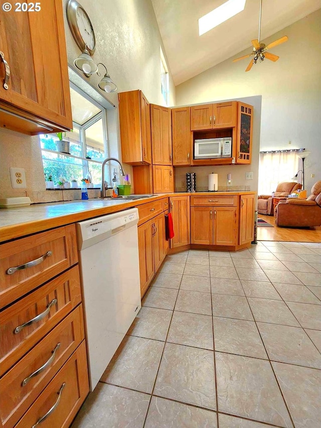 kitchen featuring light tile patterned floors, white appliances, plenty of natural light, and a sink