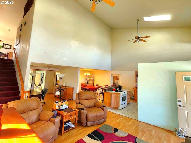 living room with stairs, a high ceiling, light wood finished floors, and ceiling fan