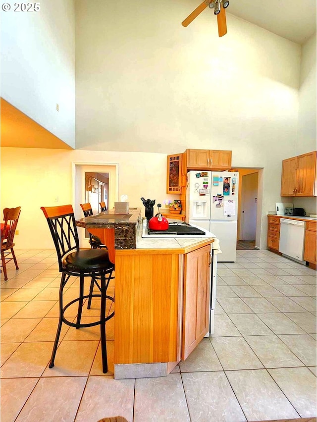 kitchen featuring white appliances, light tile patterned floors, a high ceiling, ceiling fan, and a kitchen bar