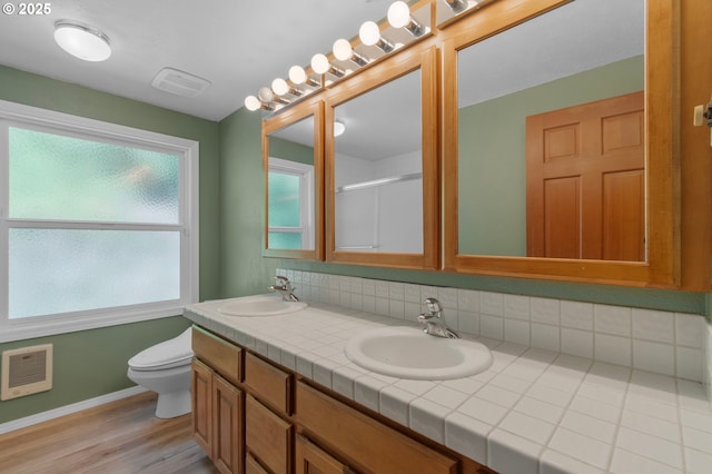 950 N Shasta Way, Clatskanie, OR 97016 - bathroom featuring double vanity, toilet, baseboards, heating unit, and wood finished floors