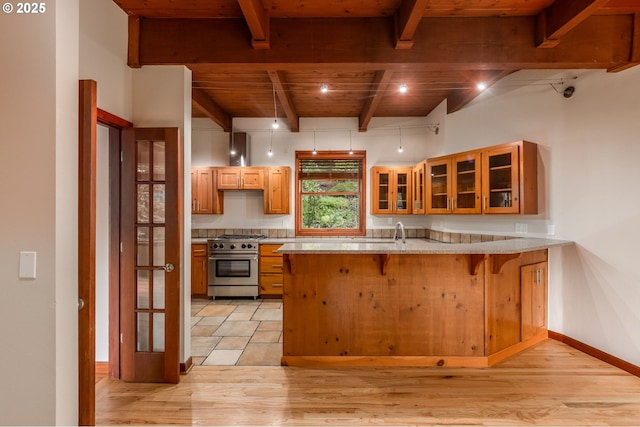 13200 NW Old Germantown Rd, Portland, OR 97035 - kitchen with high end range, wood ceiling with exposed beams, a peninsula, a kitchen breakfast bar, and light wood-style floors