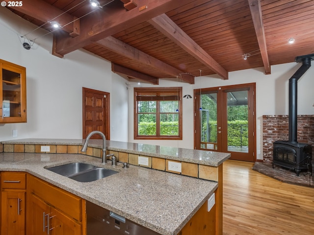 13200 NW Old Germantown Rd, Portland, OR 97035 - kitchen with a sink, wooden ceiling with exposed beams, a wood stove, light stone counters, and light wood-style floors