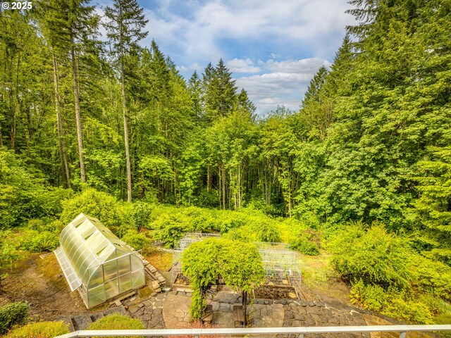 13200 NW Old Germantown Rd, Portland, OR 97035 - view of yard featuring a greenhouse, an outdoor structure, a vegetable garden, and a wooded view