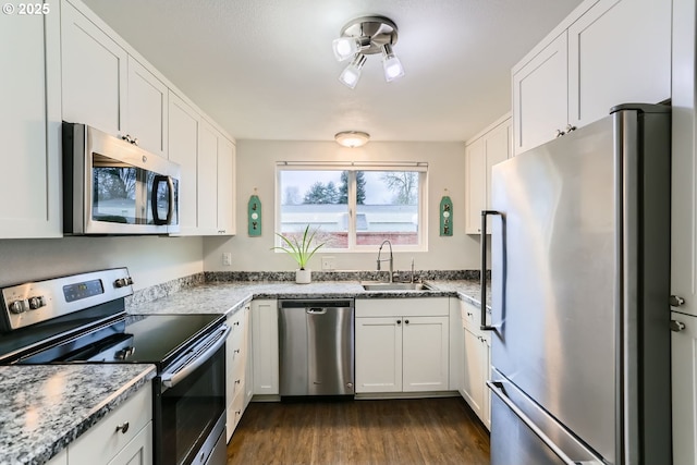 kitchen featuring dark wood-type flooring, sink, light stone counters, appliances with stainless steel finishes, and white cabinets