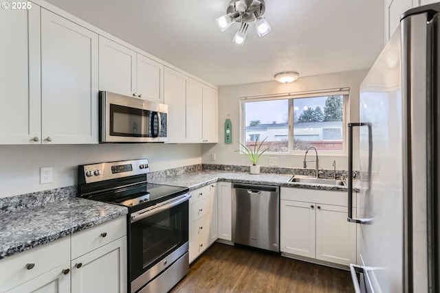 kitchen featuring sink, appliances with stainless steel finishes, white cabinetry, dark hardwood / wood-style floors, and light stone countertops