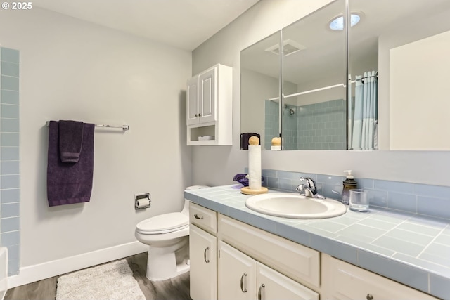 bathroom with vanity, toilet, hardwood / wood-style floors, and a tile shower